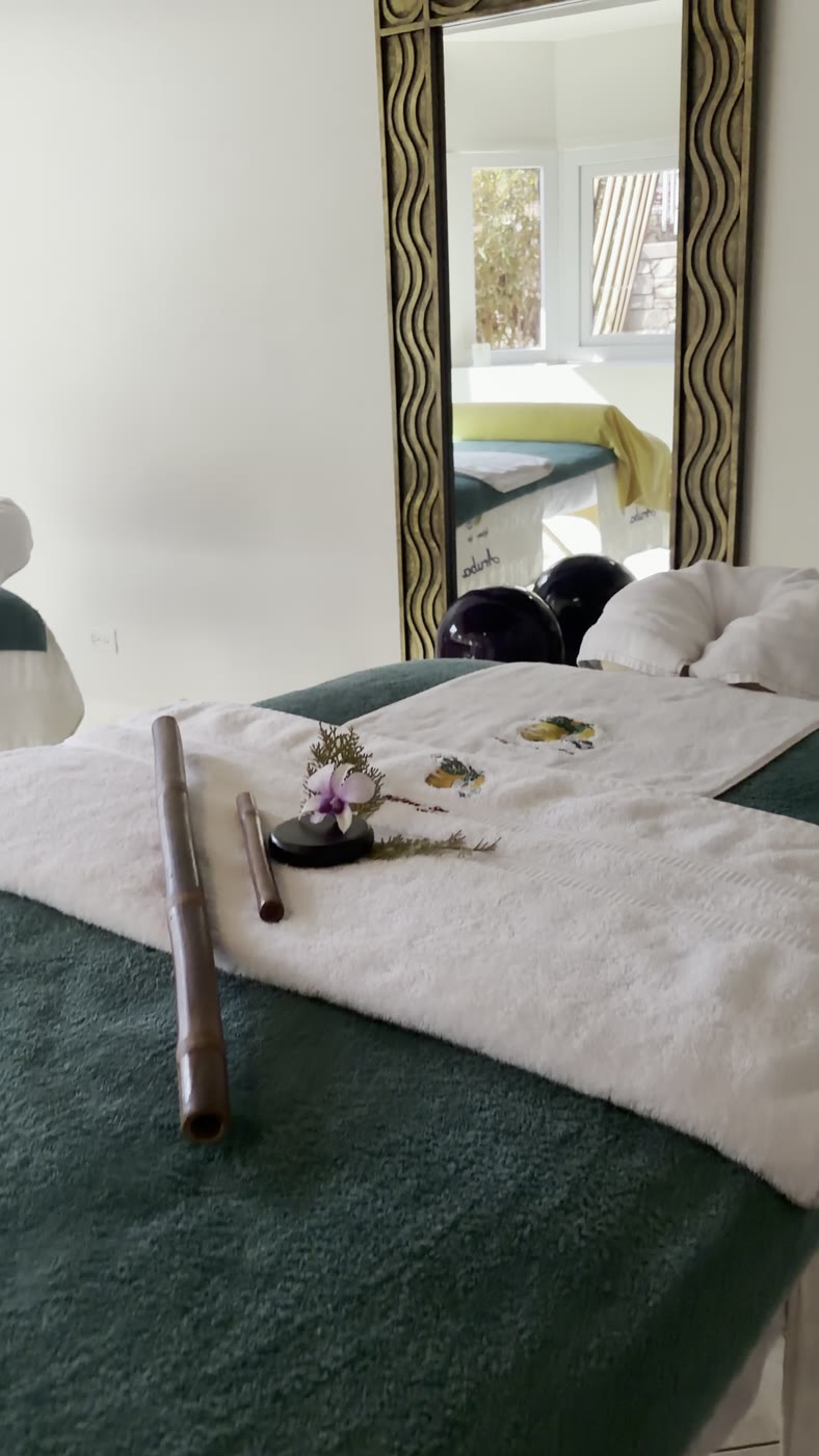 Treatment room one, with bamboo massage tools and a single orchid laid out on fresh white linens