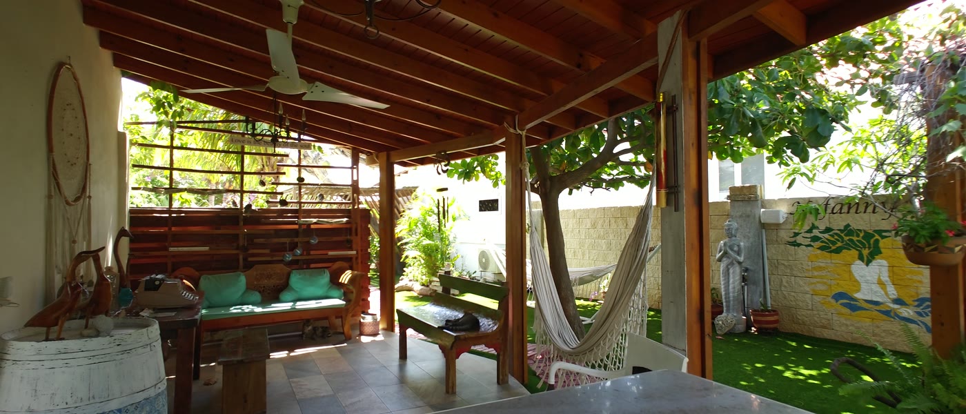The open-air reception at Nafanny Spa, with a wooden ceiling, hammock and garden view